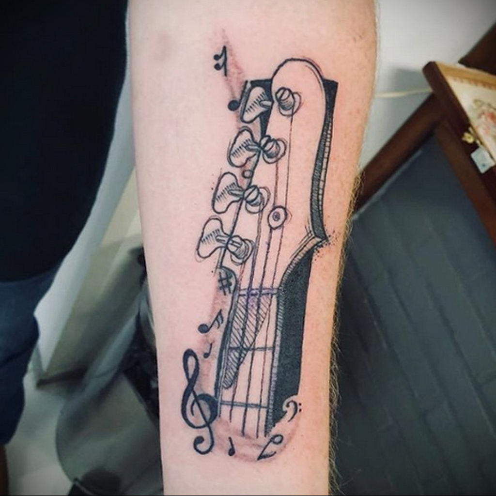 Tatuaż z fragmentem gitary i nutami - zdjęcie