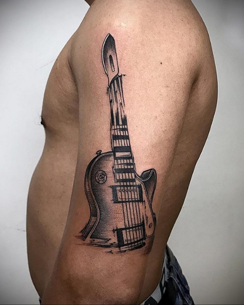 Stylowy tatuaż na gitarze na zdjęciu na ramieniu mężczyzny