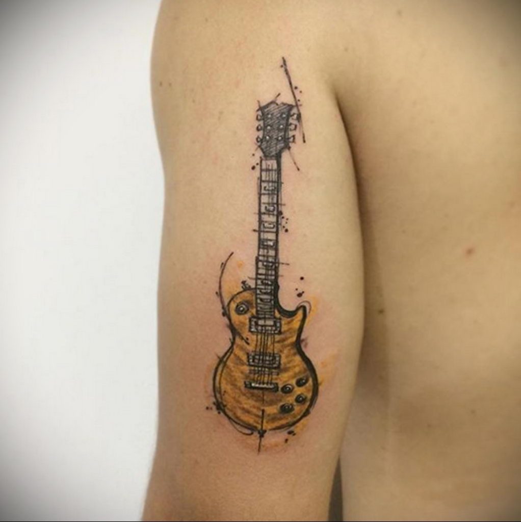Żółty tatuaż na gitarze na odcinku tricepsa - zdjęcie