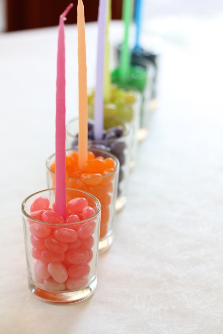 Sklenený svietnik na čajové sviečky stojaci na farebné cukríky