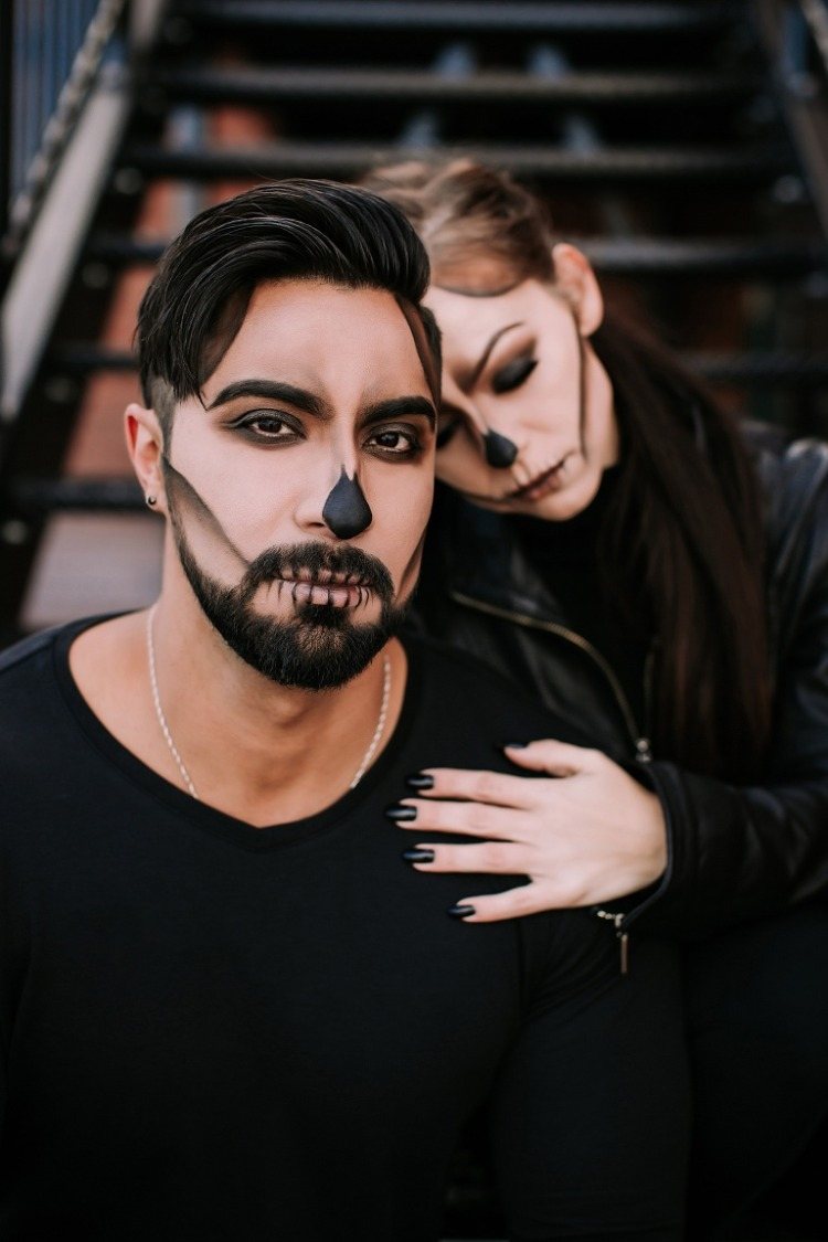 mladý pár s halloweenskou lebkou a čiernym oblečením