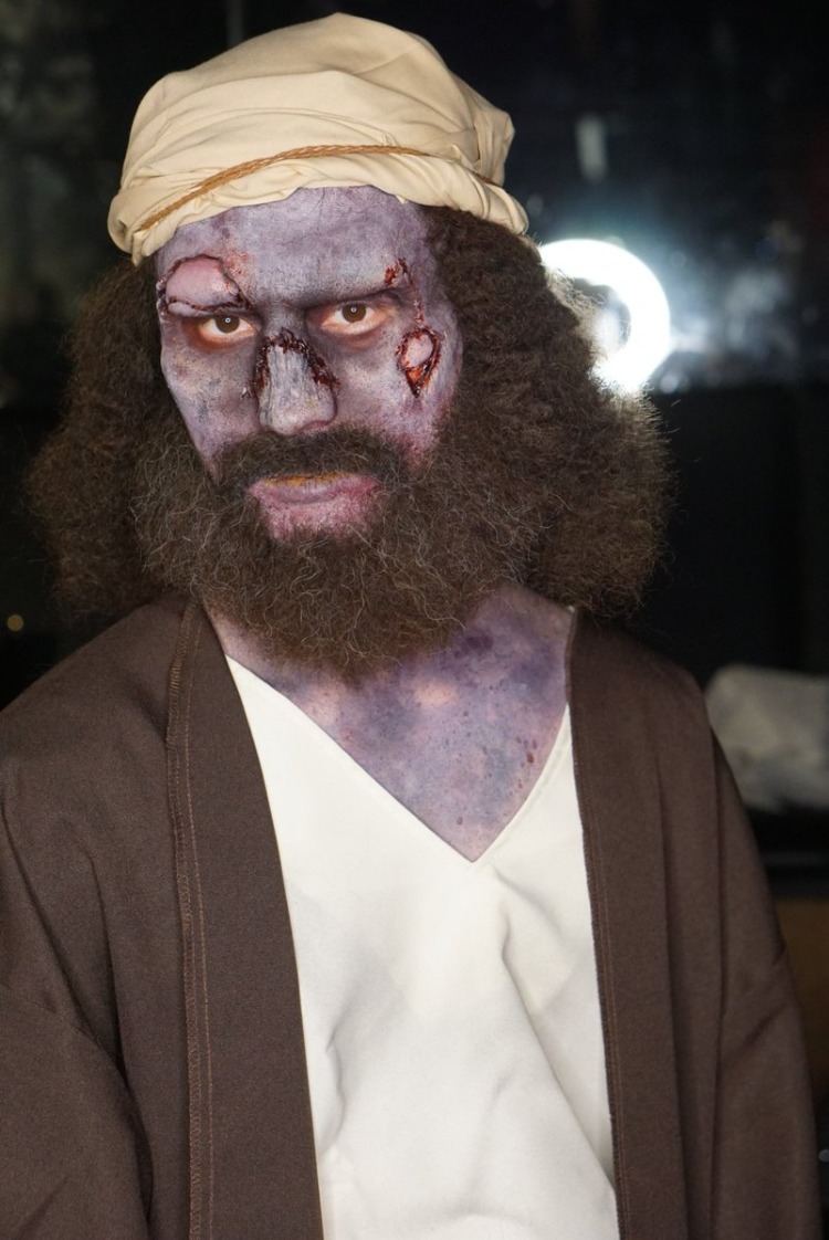 bradatý zombie, nalíčený na Halloween s ranami na tvári a farbou na koži