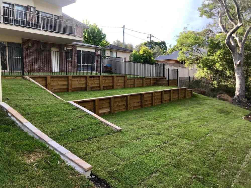 Udržiavaný trávnik v záhrade na svahu s drevenými doskami pripevnenými k svahu