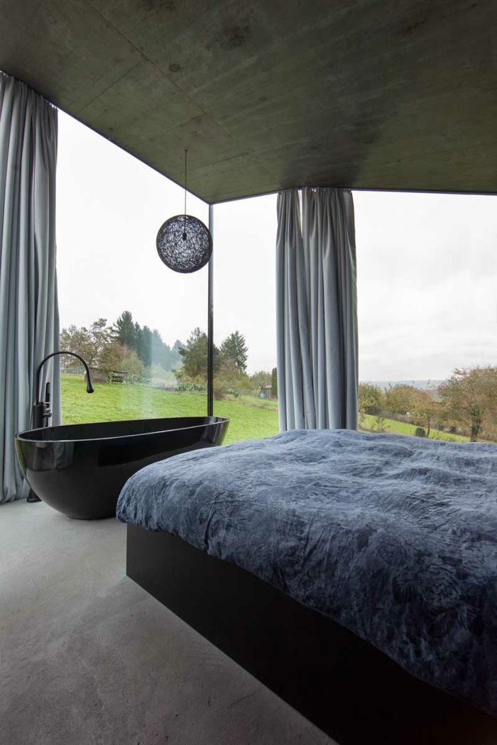 Spálňa v presklenom dome s vlastnou vaňou spálňa vaňa čierna relaxácia moderný sivý prehoz