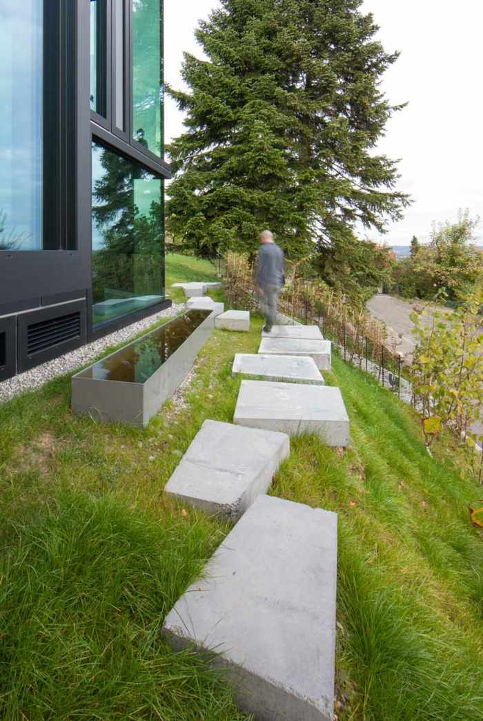 Sklenená záhradná cesta domu je tiež vyrobená z betónu záhradná cesta betónové platne trávnik svah sklenené okno