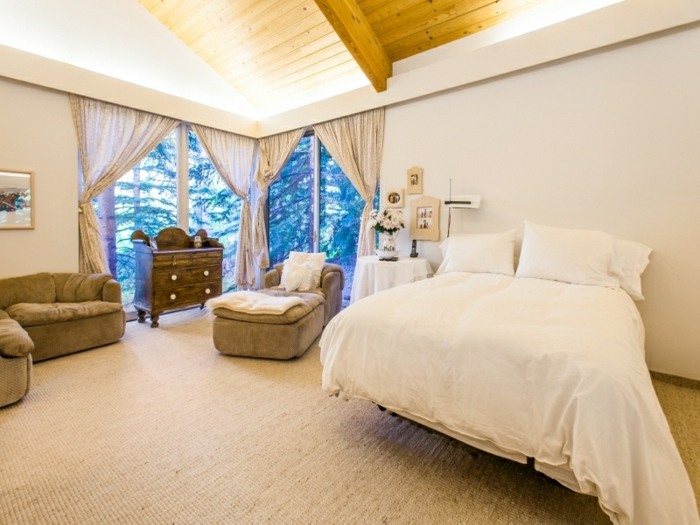 Luxusný dom v lese - v spálňach prevláda jednoduchý dizajn posteľ biely nábytok kreslo canape sivý semiš spálňa