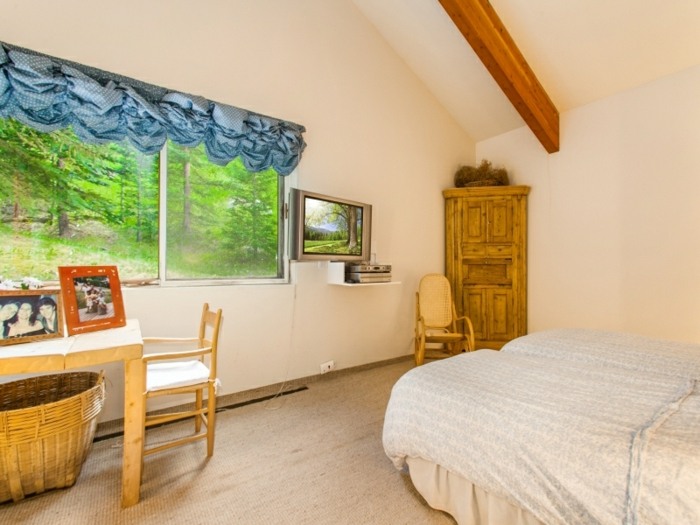 Dom v lese s dizajnom spálne z nafúknutých závesov v modrej farbe spálňa chata modrá posteľová opona drevo biela