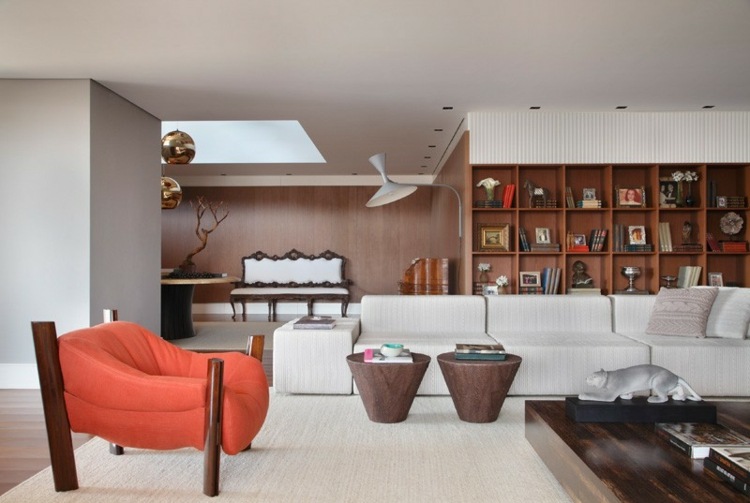 Polička z tmavého dreva zaberá stenu v obývačke Interiér domu v bielej a tmavej drevenej kresle, kožená sedacia súprava, policová polica