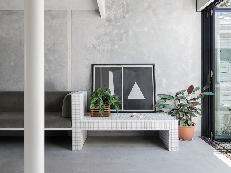 Bar pokrytý malými bielymi dlaždicami vedľa gauča a stĺpca v šedej farbe v obývacej izbe