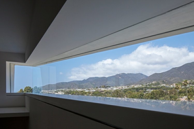 Dom s bielym nábytkom - dlhé horizontálne okno zaručuje panoramatický výhľad na krajinu zariadenie domu biela malibu horizontálne okno výhľad minimalistický