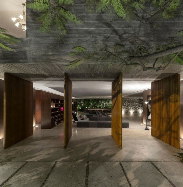 Zostava obývacej izby s drevenými dverami a rohovou stenou Obývacia izba zariadená rohová sedacia stena policový systém betónová podlaha