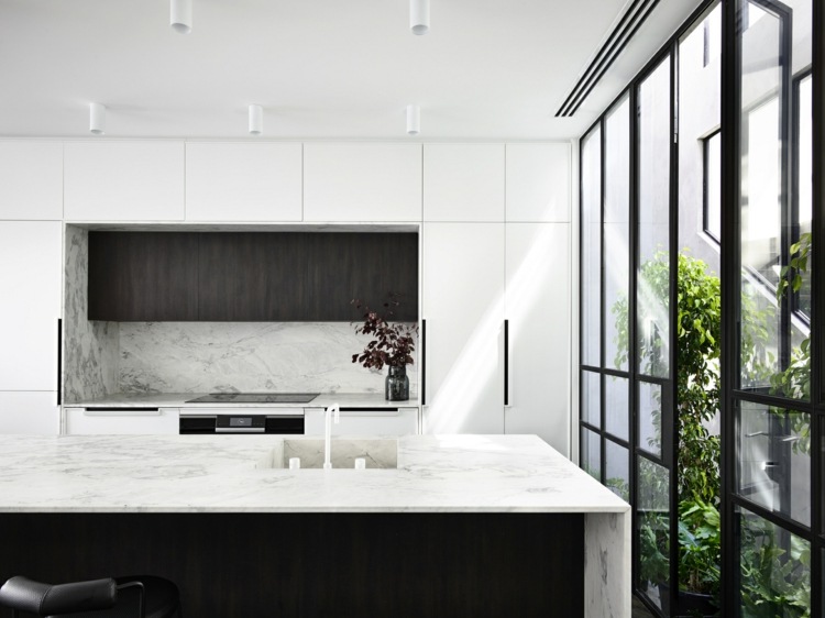 Okná orientované do vnútorného dvora a kuchynský ostrov v bielej farbe s hnedými akcentmi