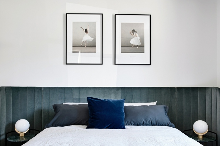 Zamatové čelo postele v spálni v modrošedých a zelených mramorových nočných stolíkoch