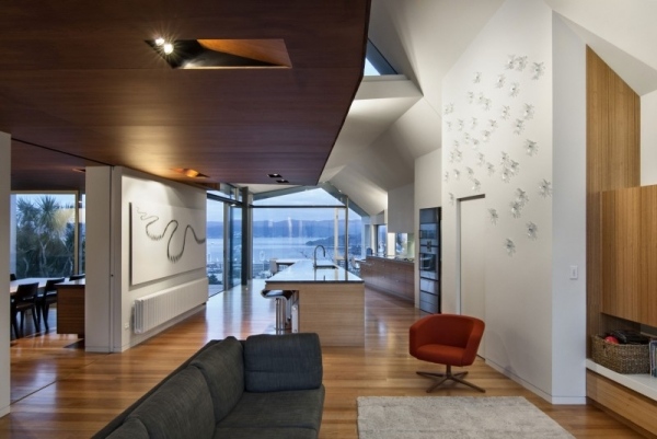 Otvorená obývacia izba, drevené obloženie, jedálenský kút a kuchynský ostrov. Červené kreslo