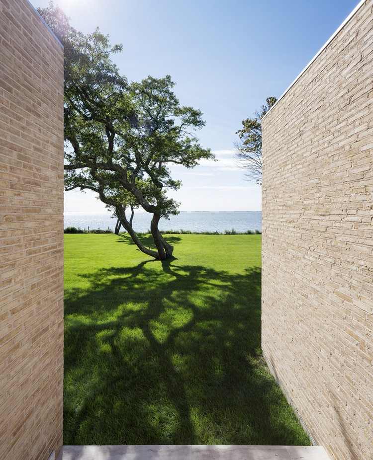 Dom s plochou strechou, svetlá tehlová fasáda zo slinku, trávnik, výhľad na oceán