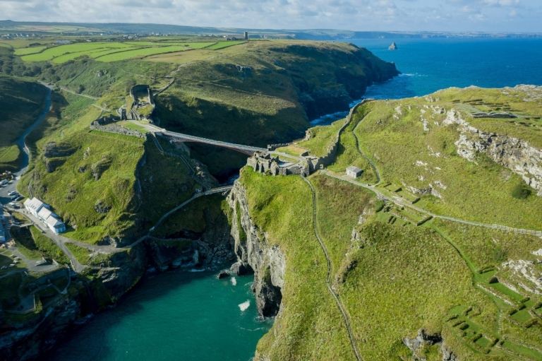 Pohľad na vták z mesta Tintagel v meste Cornwall so zelenými plochami a visiacim mostom