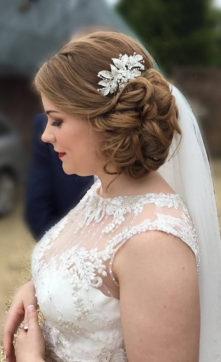 Svadobný účes zapletený na boku so závojom a vlasovými doplnkami