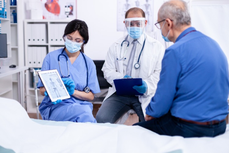 lekár a sestra staršiemu pacientovi vysvetlia účinky covid 19 na kosti