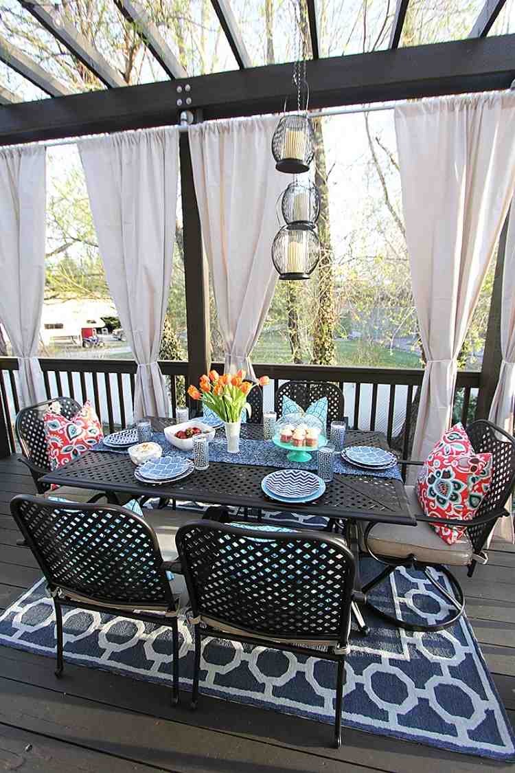 krásny dizajn so vzorovanými akcentmi a bielymi závesmi drevo-pergola-závesy-tmavé-sviečkové lampáše-závesné-koberce-záhradný nábytok-kov