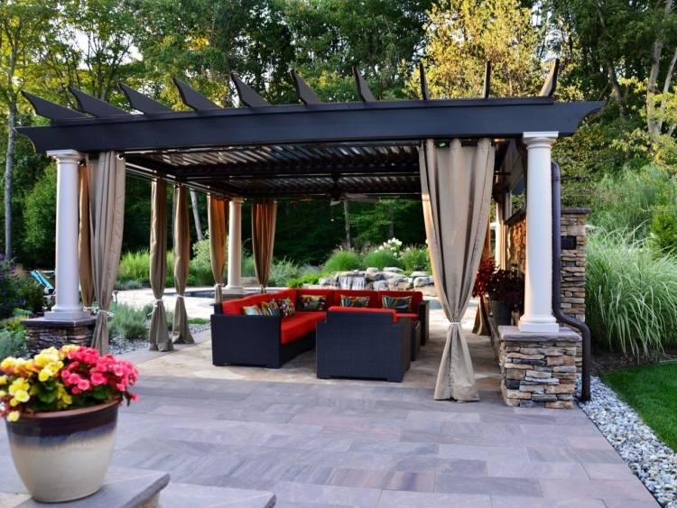 veľká pergola so štruktúrou z prírodného kameňa, ozdobnými stĺpmi a drevenými trámami na strechu drevo-pergola-závesy-záhrada-konštrukcia-stĺpy-prírodný kameň-mesto-rohové-čalúnenie-červené-vankúšové kvety