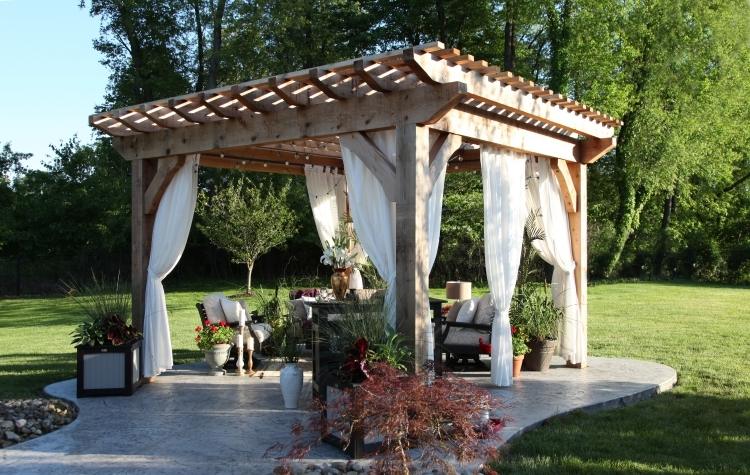 krásna pergola z masívu s krásnym záhradným nábytkom a bielymi závesmi drevo-pergola-závesy-záhrada-trávnik-už-dekorácia-rastliny-štrk-kvetináč-záhradná dekorácia-sedenie