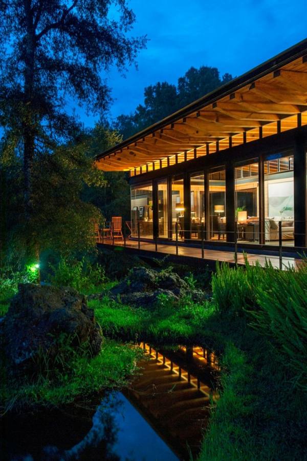 Drevený dom presklené dvere posuvné drevené osvetlenie Drevené trámy osvetľujúce fasádu s výhľadom na les