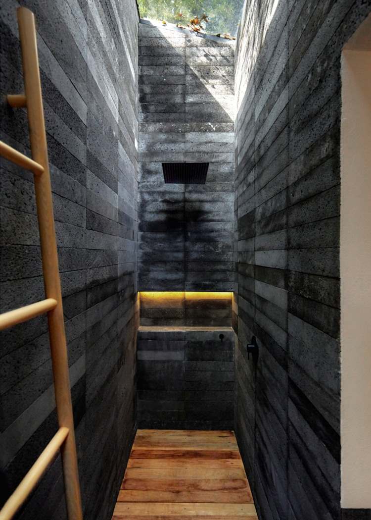 chodba opláštená tmavosivým kameňom s rebríkom a drevenou podlahou