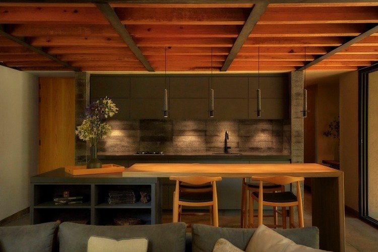 Kuchynský ostrov vyrobený z dubu za sivou sedačkou ako dizajn pre chaty v lese