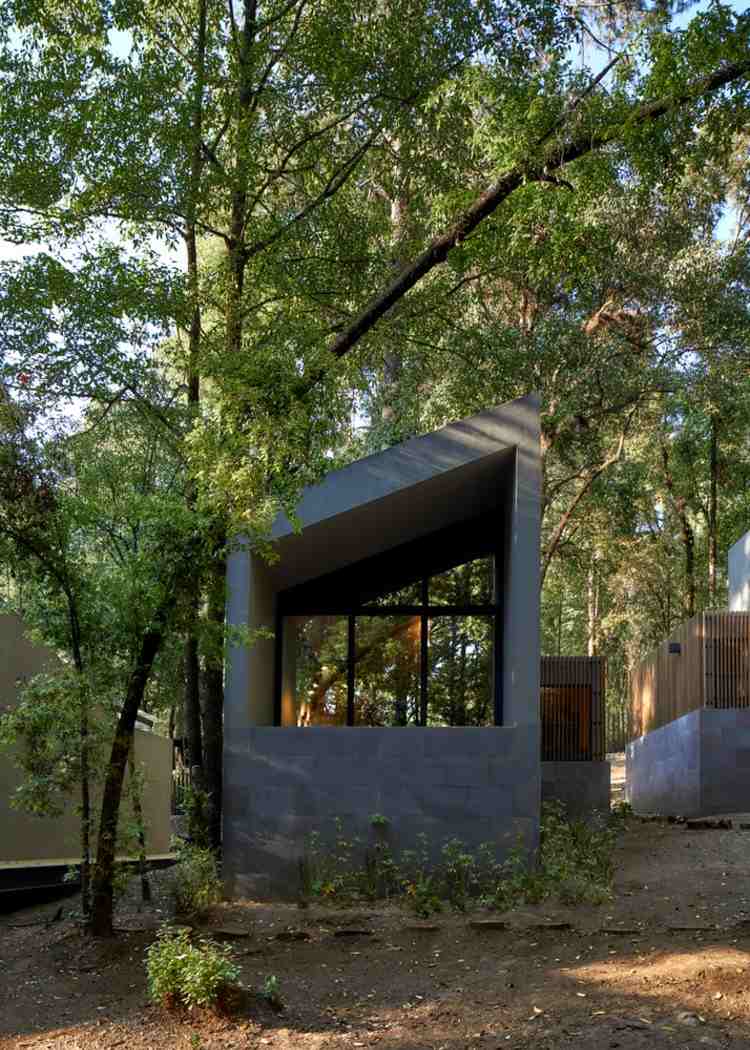 zadná časť malého domu so šikmou strechou pod stromami