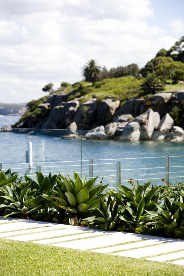 moderné malé záhradné vždyzelené rastliny kamenné obklady vždyzelené rastliny kamenné dlaždice tráva trávnik sklenené zábradlie