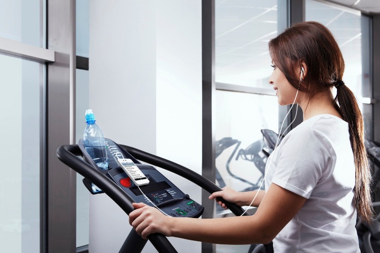 Chatovanie alebo telefonovanie pri cvičení na bežiacom páse s fľašou vody pre smartfón