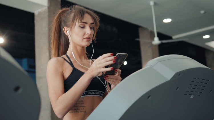 pri cvičení, chatovaní alebo telefonovaní so smartfónom žena športový bežecký pás