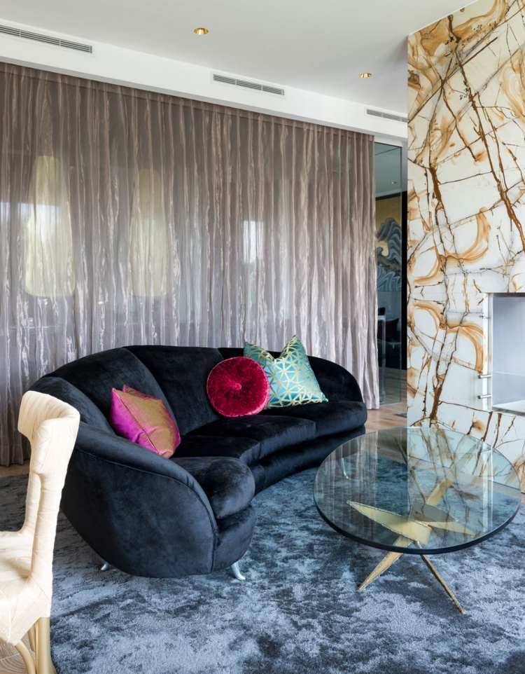 Zakrivený gauč s čalúnením z čierneho zamatu priemyselne-elegantný-luxusný-podkrovný-gauč-zakrivený-čierna-zamat-vankúše-sklenený-konferenčný stolík