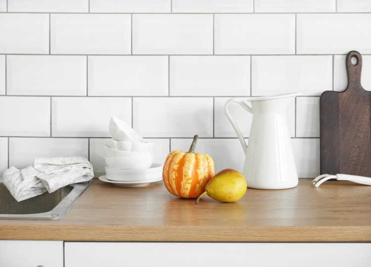 čistá kuchynská pracovná doska s ovocím a zeleninou vedľa kanvice na vodu a kuchynskej dosky