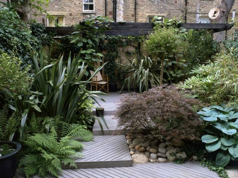 Bujné záhradné rastliny v mestskej záhrade pre tropický pocit záhradné drevené podlahy tvarované vonkajšie kríky