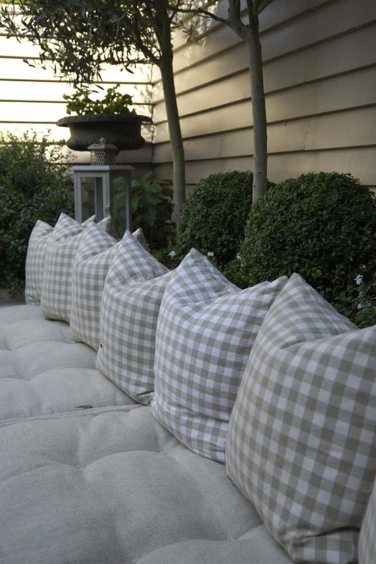 kárované vankúše v béžovej a bielej farbe usporiadané v rade malý-záhradný-dizajn-lavička-károvaný-vankúš-béžovo-biely