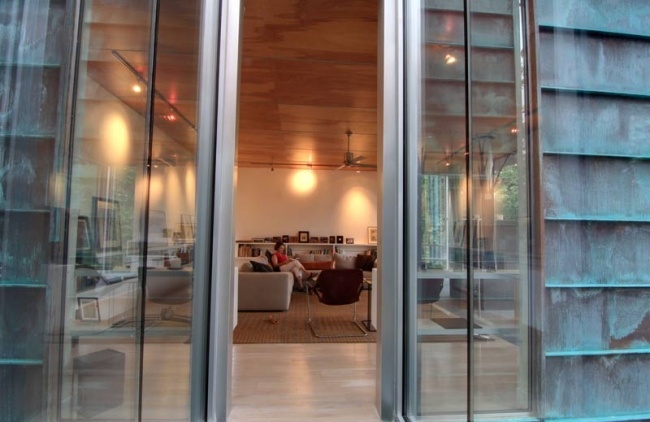 Dom so sklenenou medenou vonkajšou stenou potiahnutou v lese