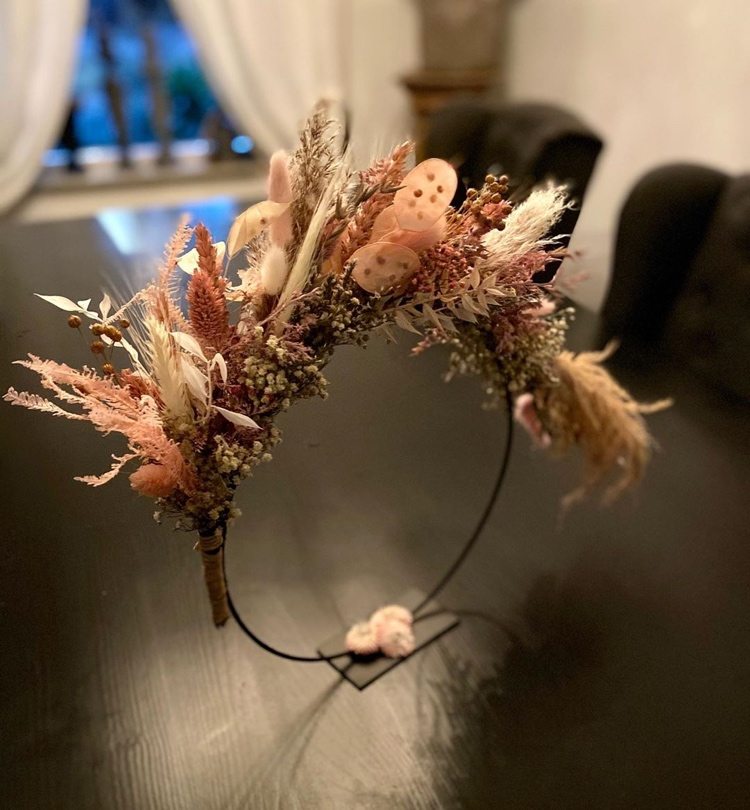 Veniec so sušenými kvetmi a trávou stojaci na stole