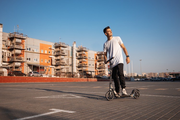šťastne vyzerajúci dospievajúci chlapec s elektrickým bicyklom v mestskom prostredí s príjemným životným prostredím