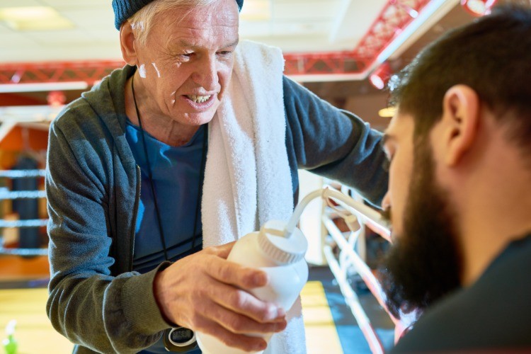 Tréner boxera mu počas tréningu dáva čerstvú vodu