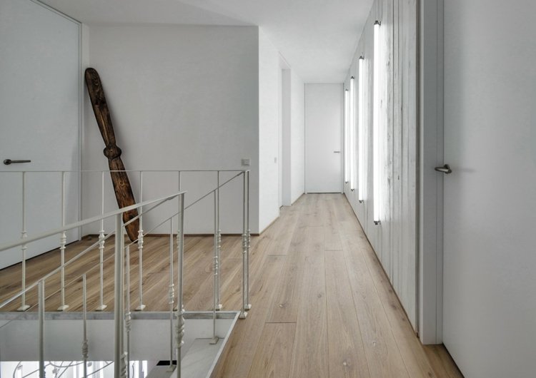 Chodba s bielym stenovým dizajnom pre minimalistický nádych štrk-akcent-stena-biela-hala-minimalistický-laminát-deko-stena-dizajn-neutrálny