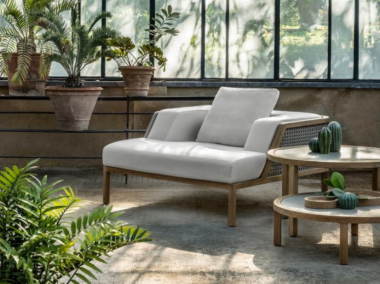 pohodlné čalúnené kreslo z ratanu a dreva obklopené kvetináčmi a kaktusmi