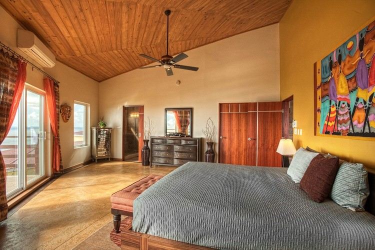 žltá akcentovaná stena za posteľou a dlažba v kamennom vzhľade stredomorský-nástenný-dizajn-spálňa-žltý-akcent stenový-drevený nábytok