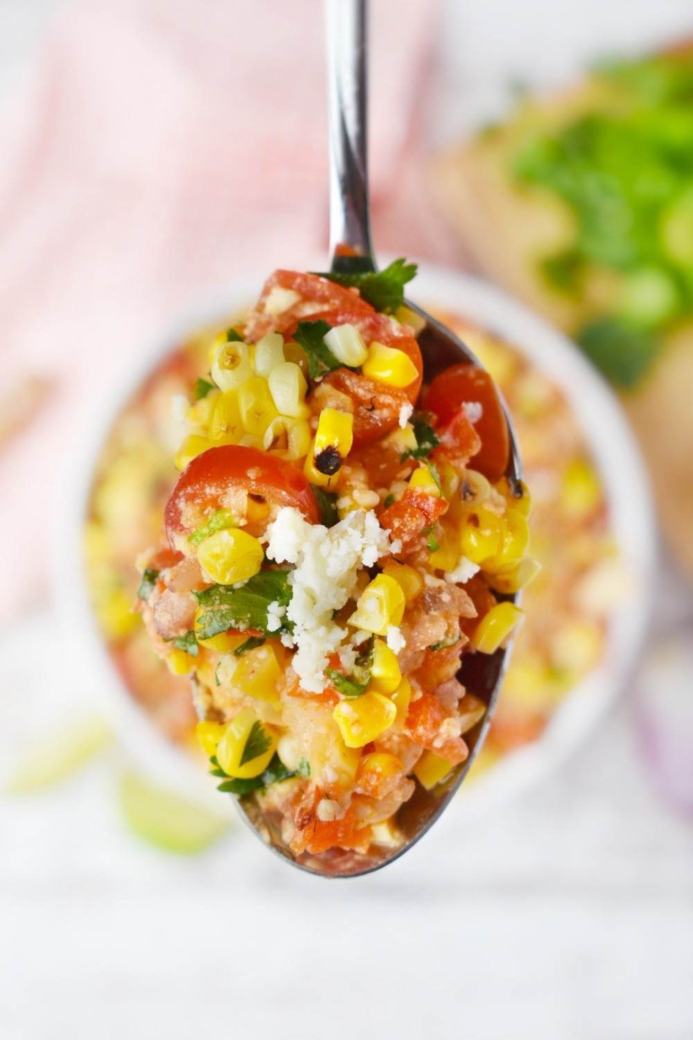 polievková lyžica naplnená zdravými prísadami, ako je zelenina kukurica, cherry paradajky, ovčí syr, quinoa a korenie