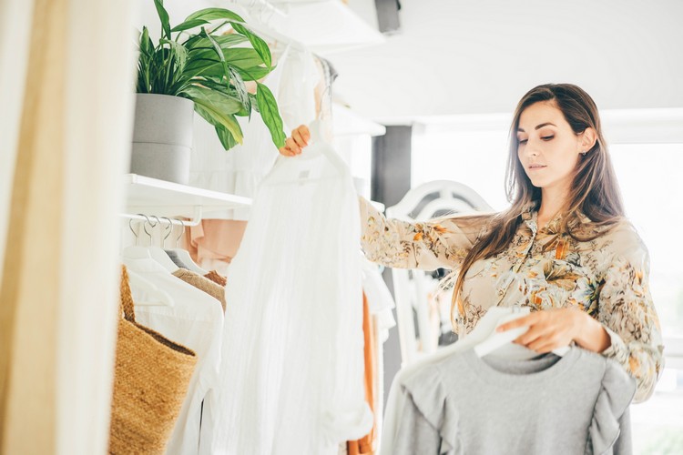 Žena aranžuje šatník so základným oblečením