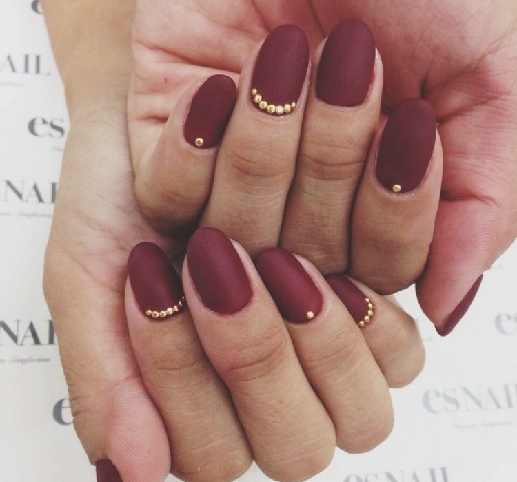 tmavo červený lak na nechty a zlaté perly na podklade nechtov moderné-nechty-manikúra-tmavo-červená-matná-lak-na nechty-zlaté-perly