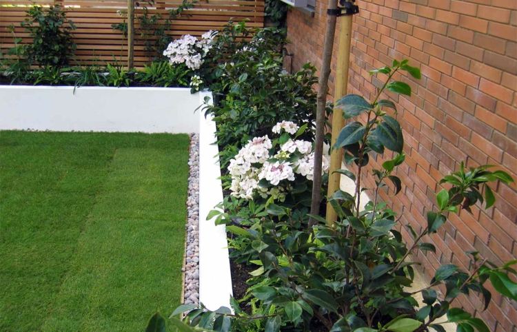 Pre tento moderný záhradný dizajn boli ako akcenty použité kamienky moderný záhradný dizajn-kamene-akcent-kamienky-biela-stena-vyvýšená posteľ-trávnik