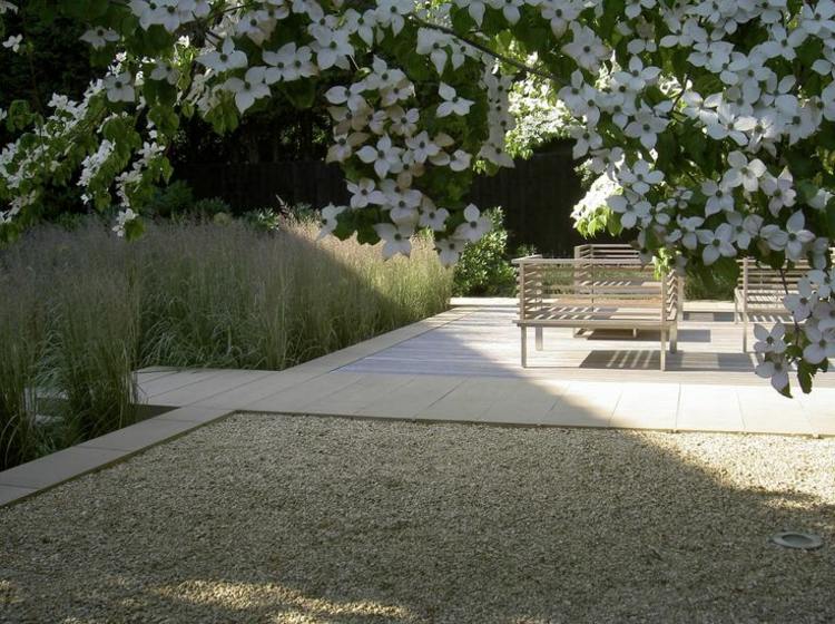 Myšlienka záhradného dizajnu - kamenné dosky, štrk, tráva a drevené lavičky moderný-záhradný-dizajn-kamene-kamienky-graeser-lavičky-jarný kvet-strom