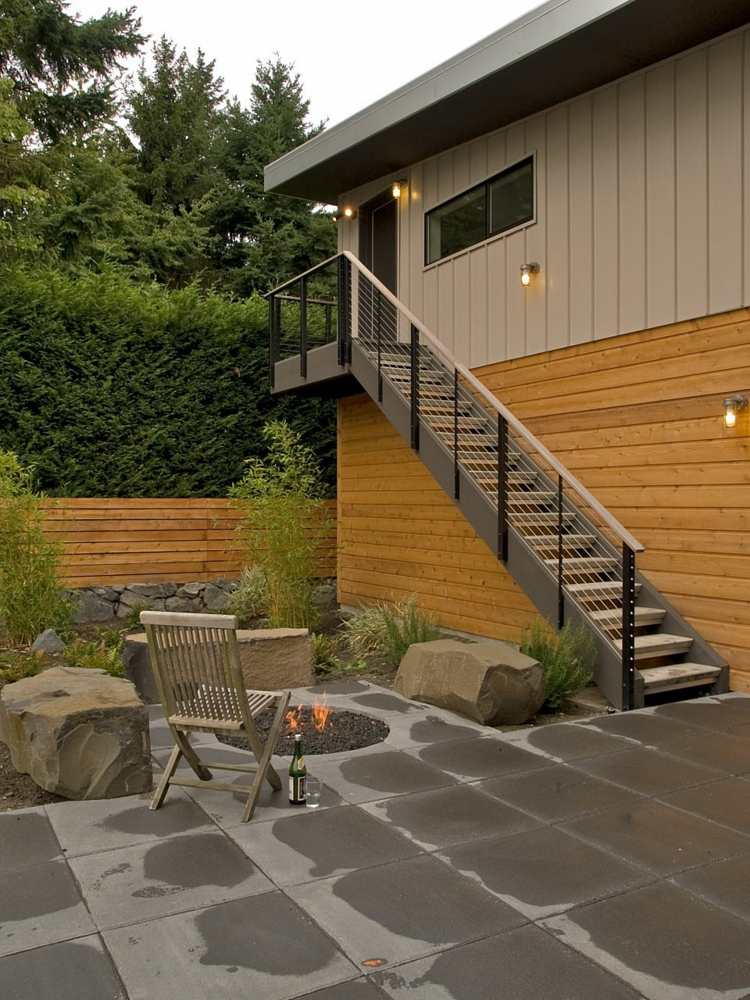 Veľké kamene slúžia ako lavičky pri krbe moderný-záhradný-dizajn-kamenné sedadlá-nápad-krb-deko-štrk-drevo-fasáda