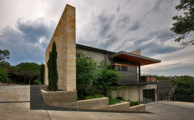 Kamenná stena domu s plochou strechou stavia modernú horskú vidiecku rezidenciu zapustenú do svahu